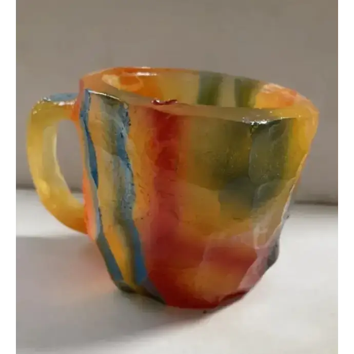 A translucent, rainbow-colored mug with a textured, faceted surface and a glossy finish.