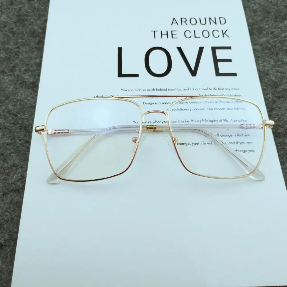 Gold-toned rectangular-framed glasses with clear lenses and subtle metallic detailing on the temples.