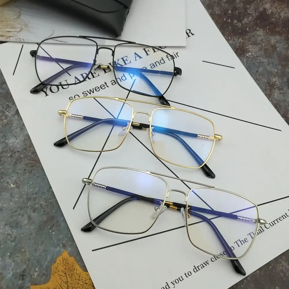 Three pairs of rectangular-framed eyeglasses with blue-tinted lenses and metallic rims in black, gold, and silver finishes.