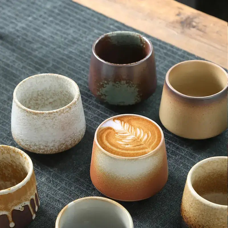 A ceramic coffee cup with a gradient glaze transitioning from warm orange to white, featuring intricate latte art on its surface.