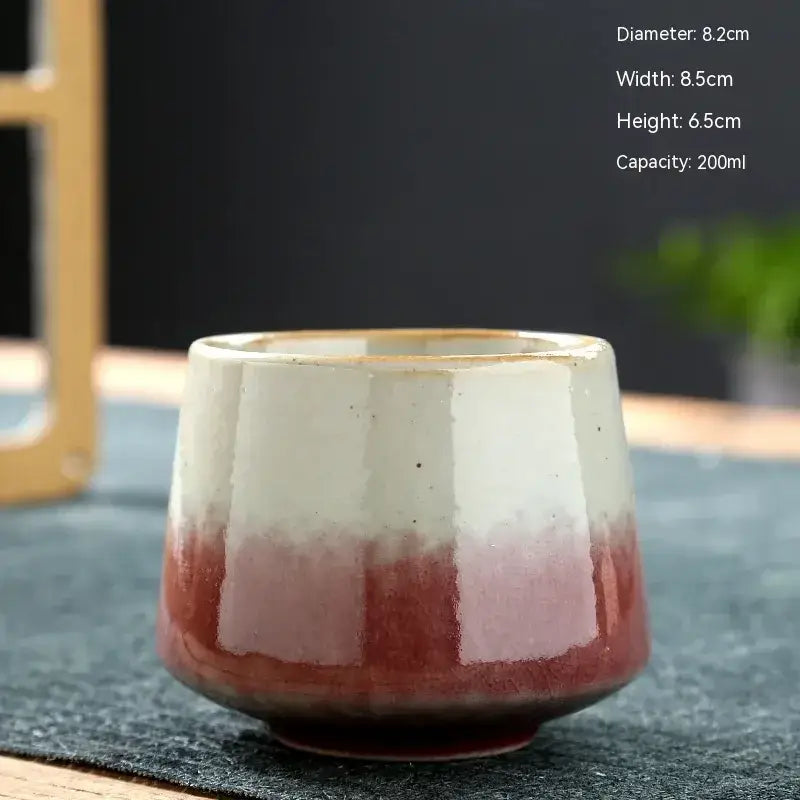 A ceramic tea cup with a gradient glaze transitioning from white to deep red, featuring subtle vertical ridges and a gold-rimmed rim.