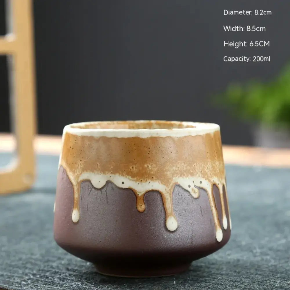 A rustic ceramic teacup with a brown base and caramel-colored glaze that drips down its sides, featuring subtle white accents.
