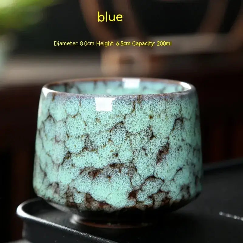 A ceramic tea cup with a crackled turquoise glaze and dark brown accents, featuring a glossy finish.