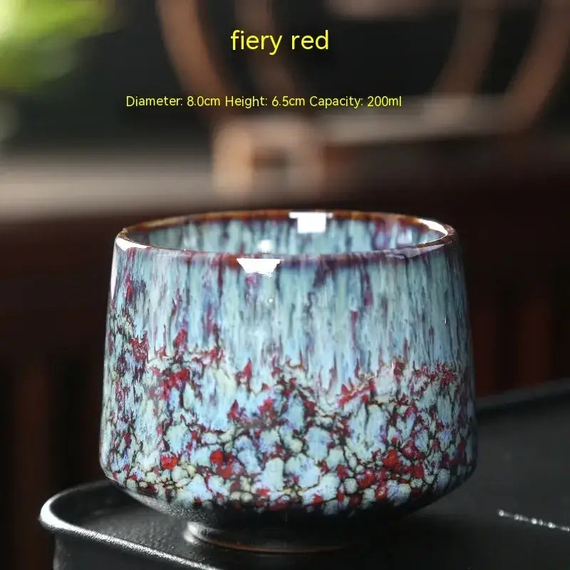 Fiery red ceramic tea cup with a textured glaze featuring swirling blue and crimson patterns.
