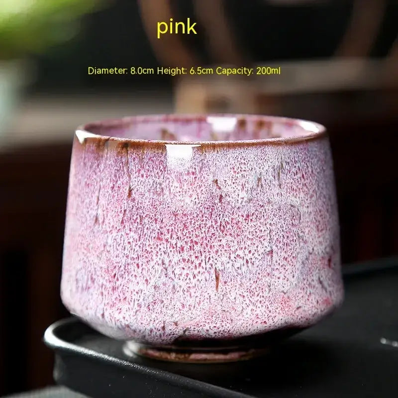 A handcrafted ceramic tea cup with a speckled pink glaze and brown rim, featuring dimensions of 8.0cm in diameter and 6.5cm in height, holding 200ml capacity.