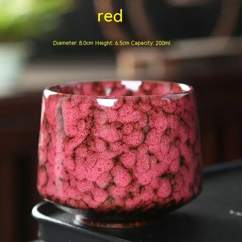 A vibrant red ceramic tea bowl with a textured, bubble-like glaze and a glossy finish.