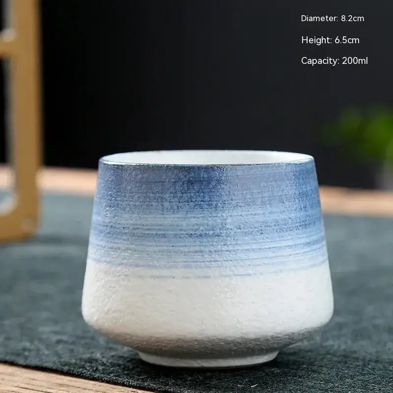 A ceramic teacup with a gradient blue and white glaze, featuring subtle horizontal striations.