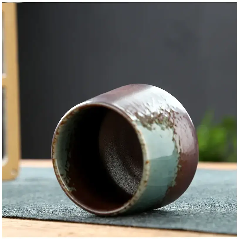 A ceramic tea cup with a rustic, handcrafted finish featuring a gradient glaze that transitions from deep brown to muted teal.