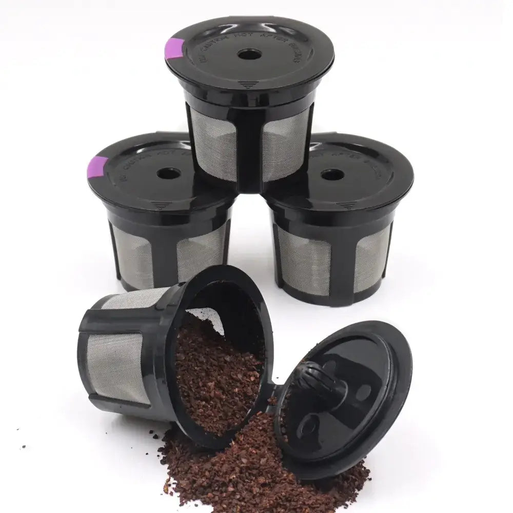 Black k-cup coffee filters with mesh interiors and purple accents on the lids, one tipped over to show ground coffee inside.