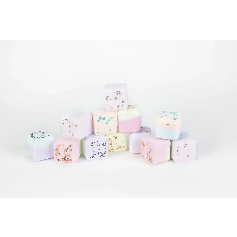 Pastel-colored bath bombs with speckled, glittery toppings in soft pinks, blues, and whites.
