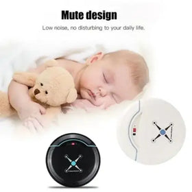 Black circular robot vacuum with blue glowing center and white cross design on top