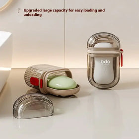 Transparent plastic soap dish with a beige base and red accent strap, featuring an oval-shaped design for easy loading.