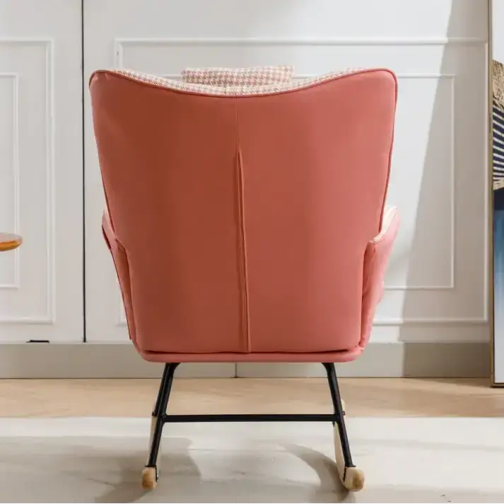 A coral-pink upholstered rocking chair with a houndstooth-patterned cushion and black metal frame.