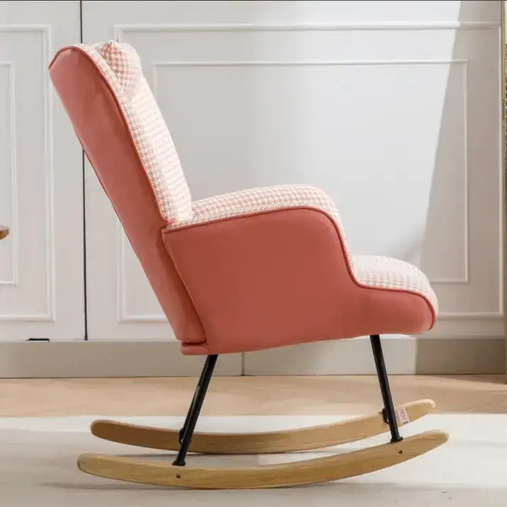 A cozy peach-colored rocking chair with a houndstooth patterned backrest and seat, supported by black metal legs and light wood rockers.