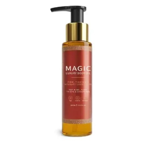 A sleek amber glass bottle with a gold pump dispenser, labeled ’magic luxury body oil,’ contains golden-hued oil.