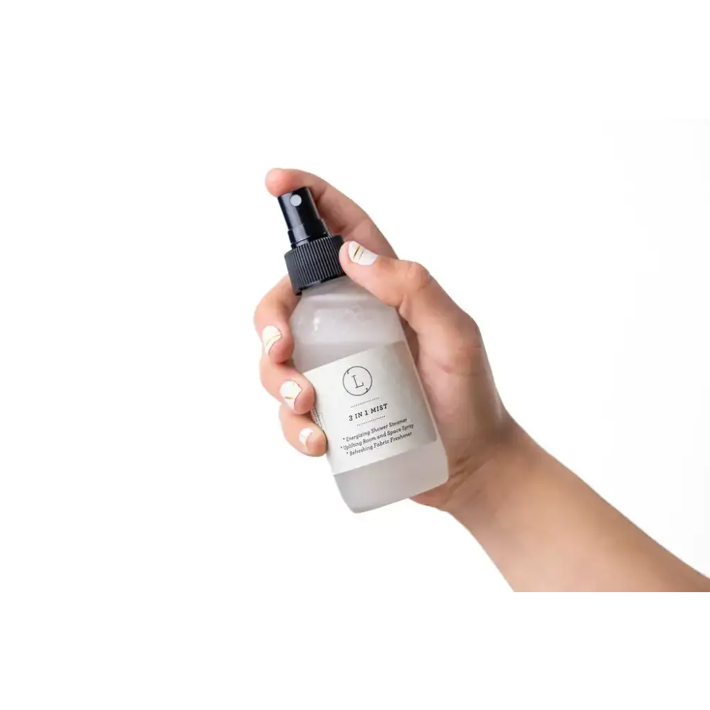 A frosted glass bottle with a black spray nozzle and minimalist white label, holding a 3-in-1 mist product.