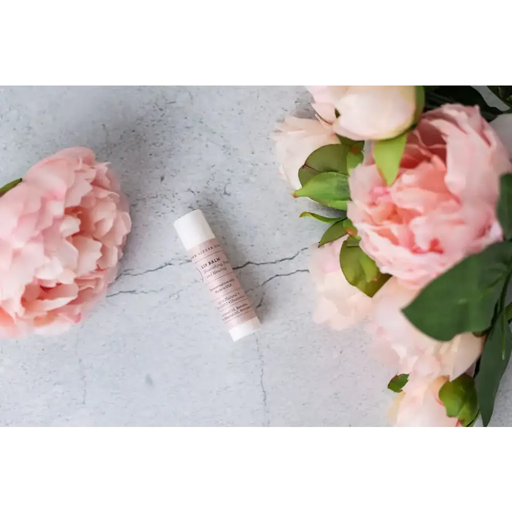 A sleek, minimalist tube of lip balm with a white cap and soft pink labeling.