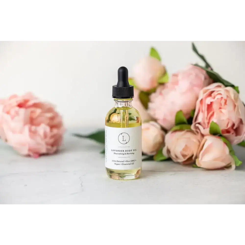 A clear glass bottle of lavender body oil with a black dropper cap and white label, containing golden-yellow liquid.