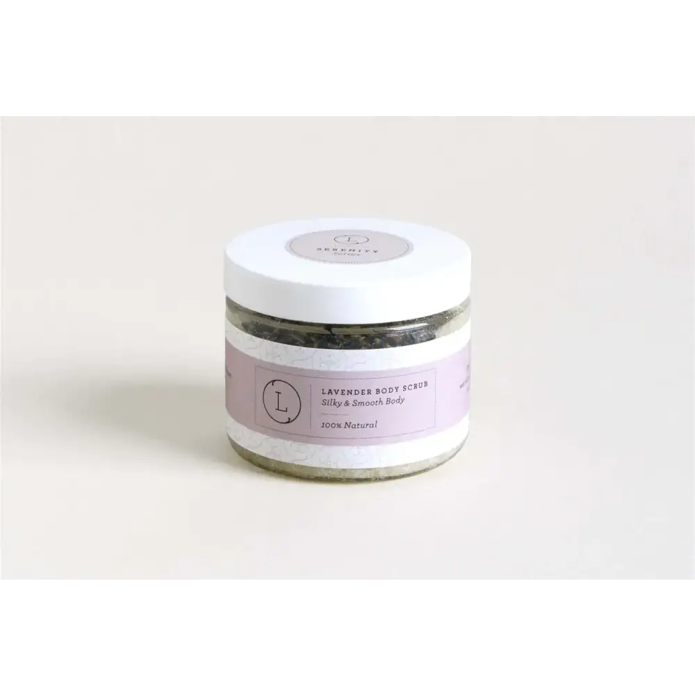 A lavender-scented body scrub in a clear glass jar with a white lid and purple label, featuring the brand name ’serenity’ and the text “100% natural.”