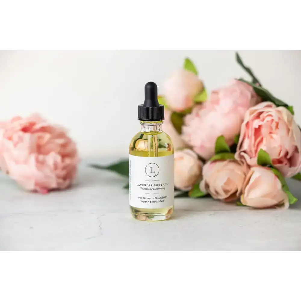 A clear glass bottle of lavender body oil with a black dropper cap and white label, containing golden-yellow liquid.