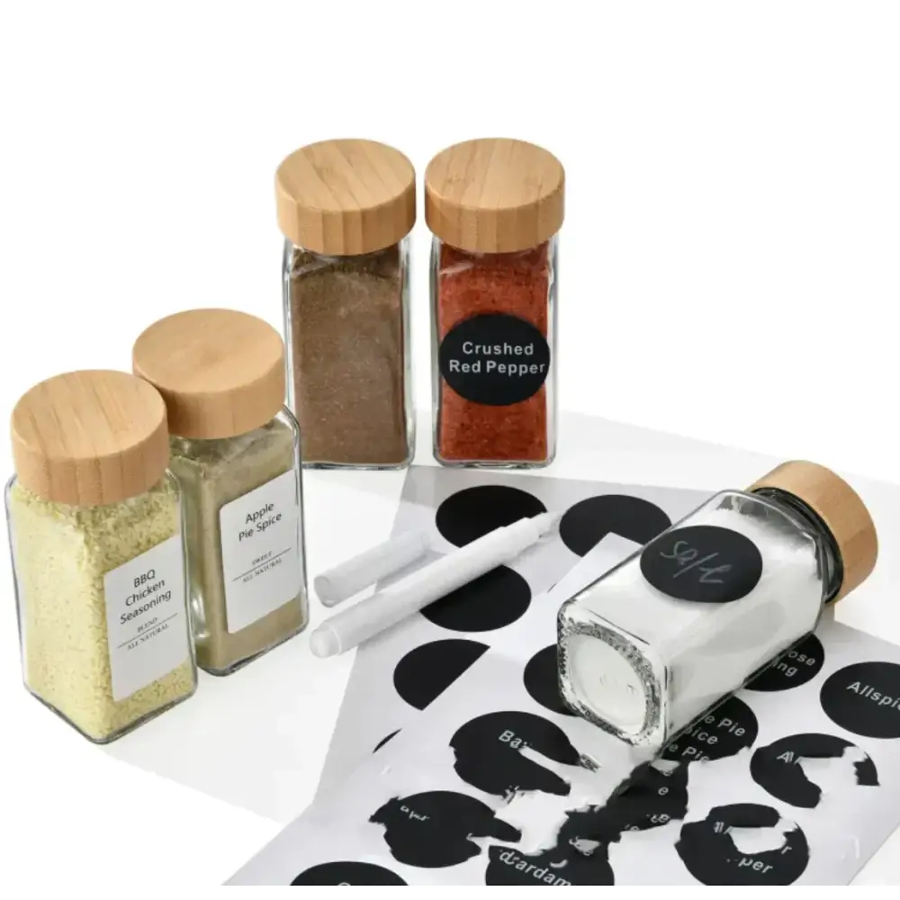 Clear glass spice jars with natural wood lids and black circular labels.