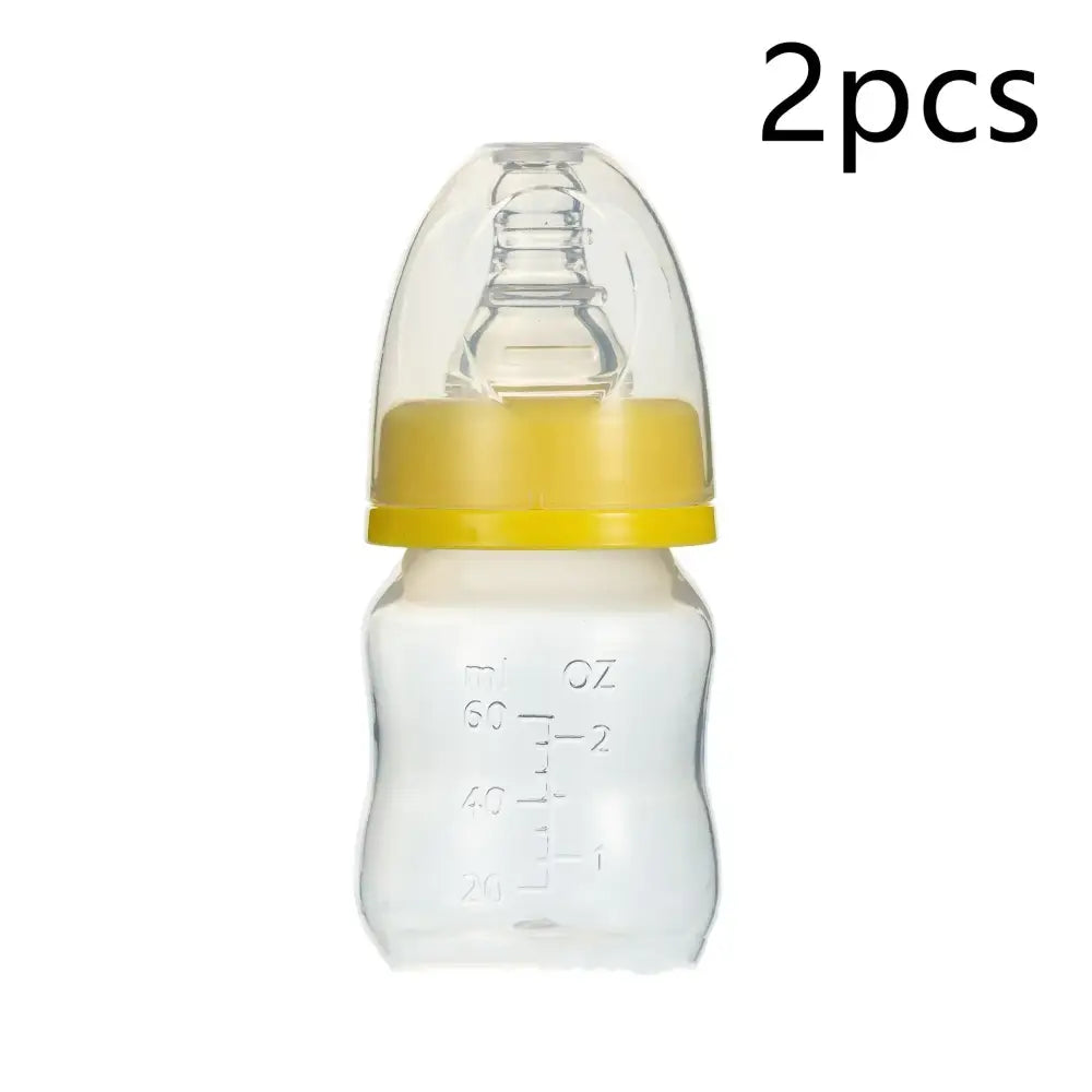 Clear plastic baby bottle with a yellow silicone ring and transparent nipple, marked with measurement lines in ml and oz.