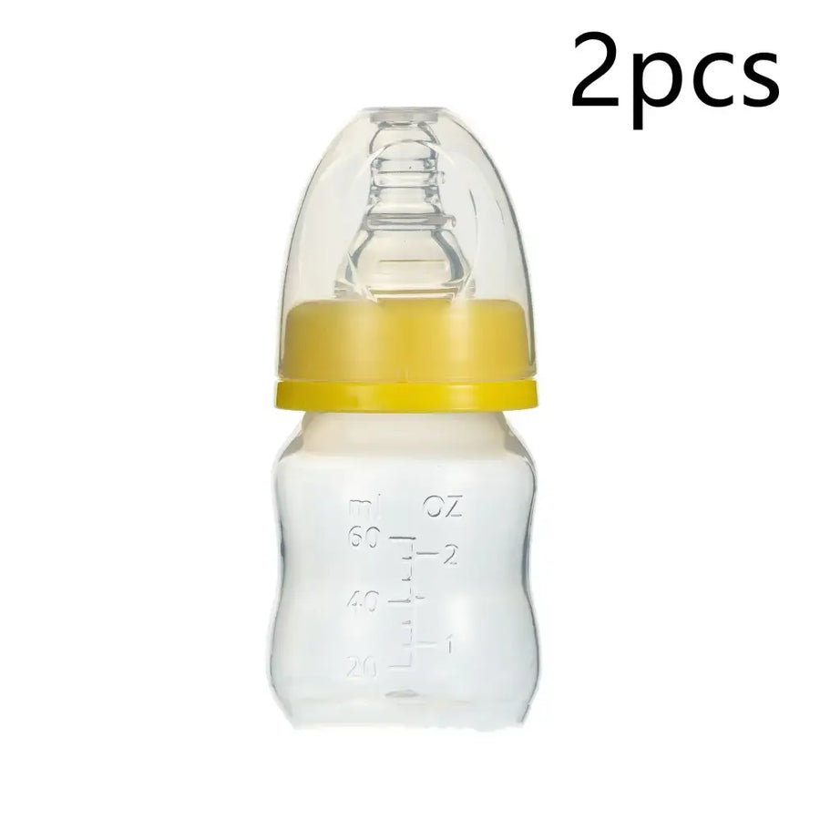 Clear plastic baby bottle with a yellow silicone ring and transparent nipple, marked with measurement lines in ml and oz.