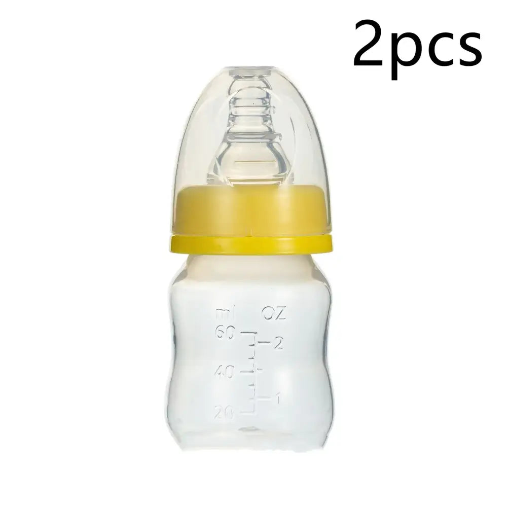 Clear plastic baby bottle with a yellow silicone ring and transparent nipple, marked with measurement lines in ml and oz.