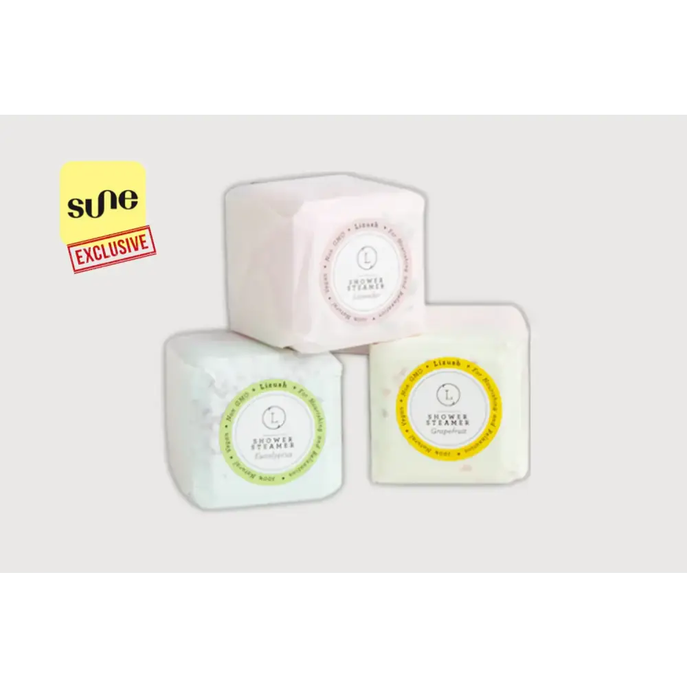 Three cube-shaped shower steamers, each wrapped in a soft pastel-colored paper with circular labels indicating their scent—lavender, lemon, and gingerbread.