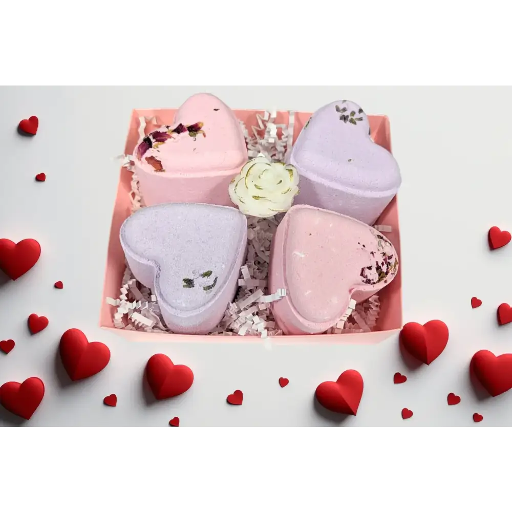 Pink and lavender heart-shaped bath bombs with floral accents nestled in a pink box.