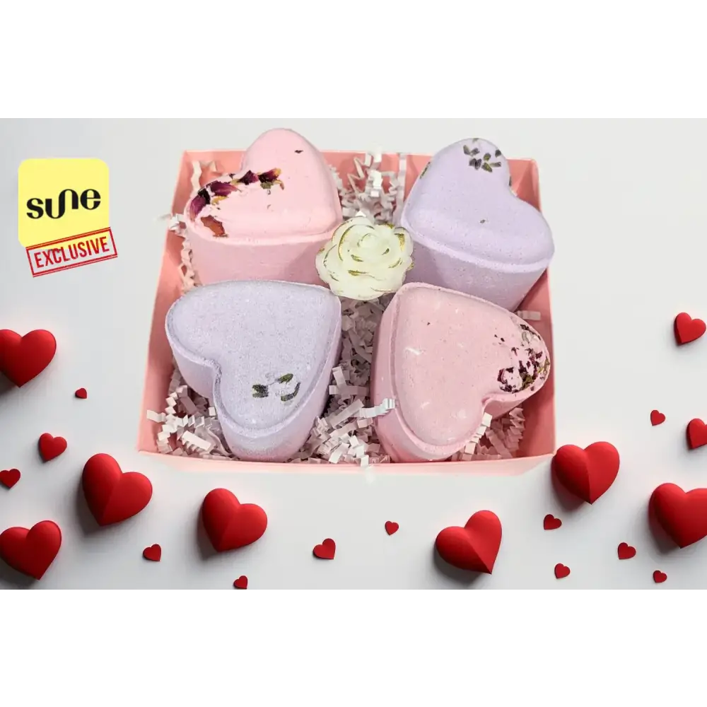 Pink and lavender heart-shaped bath bombs with floral accents nestled in a pink box.