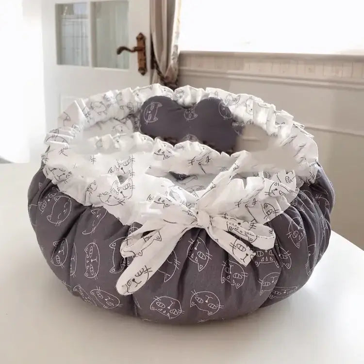 Gray cat-themed pet bed with white ruffled trim and a matching bow.