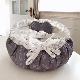 Gray cat-themed pet bed with white ruffled trim and a matching bow.