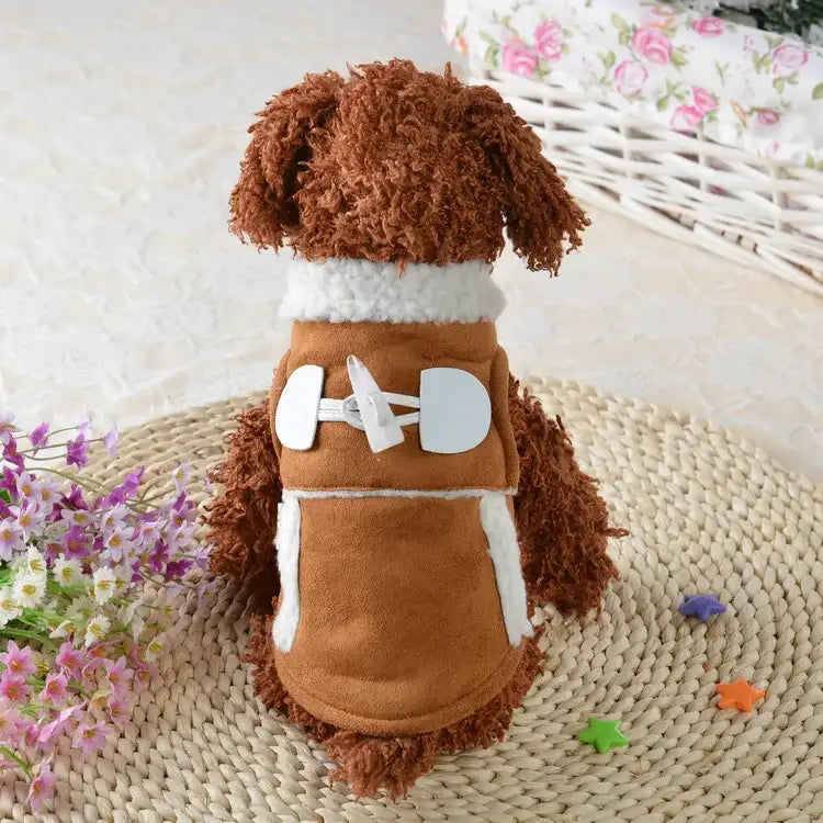 Brown fluffy dog wearing a tan suede vest with white faux fur trim and large white toggle closures.