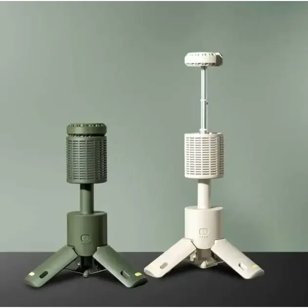 Two portable camping stoves, one in olive green and the other in off-white, each featuring a tripod base with adjustable height.