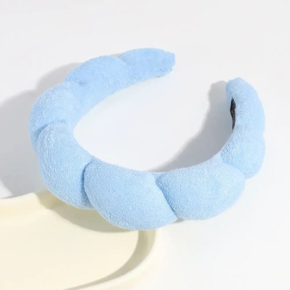 A soft, light blue twisted fabric headband with a plush texture.