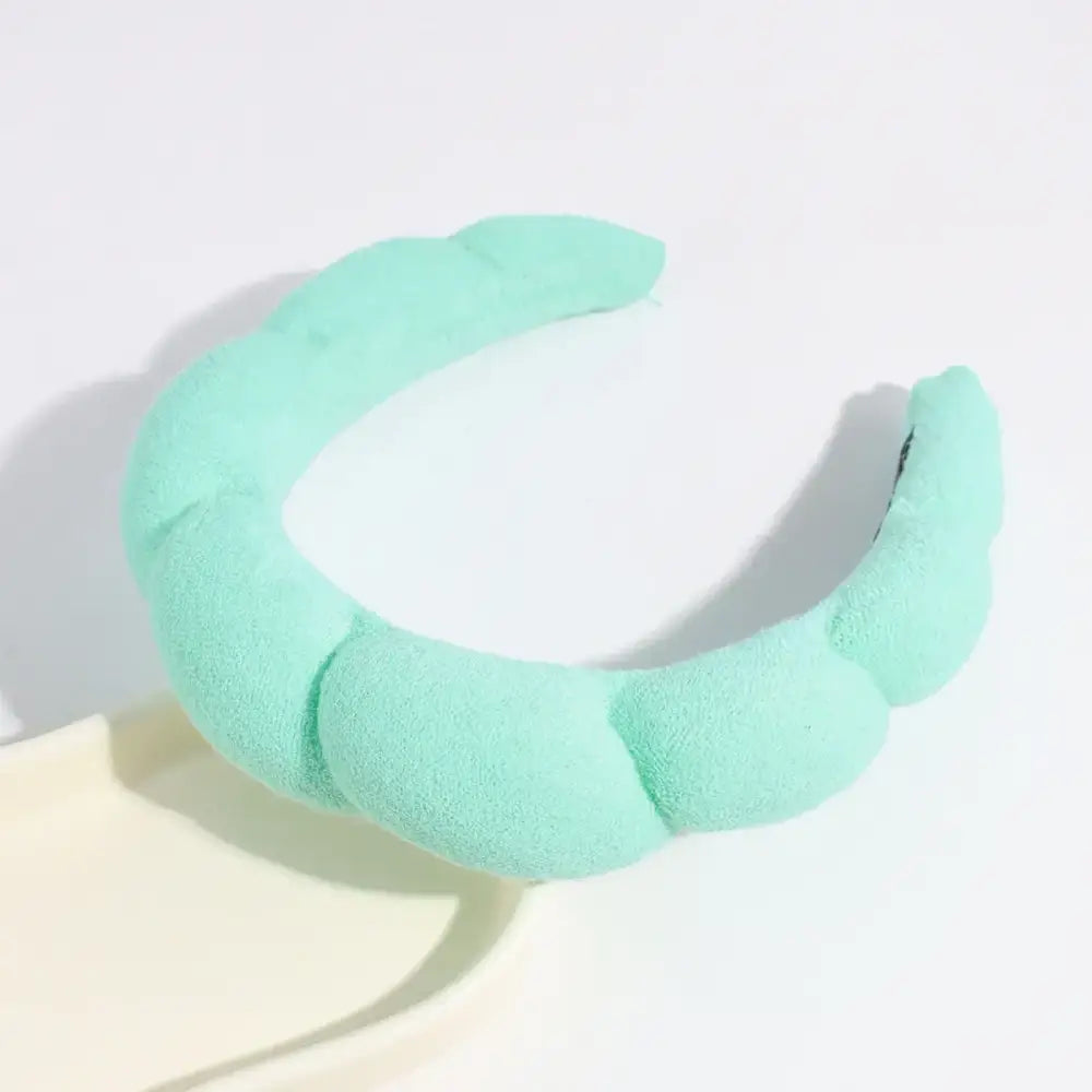 A soft, mint green, plush headband with a segmented, cloud-like design.