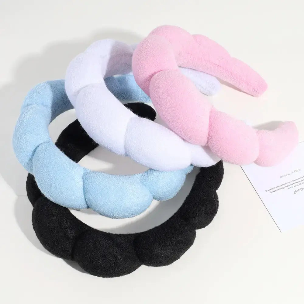 Soft, plush, twisted headband in pastel pink, light blue, and black.