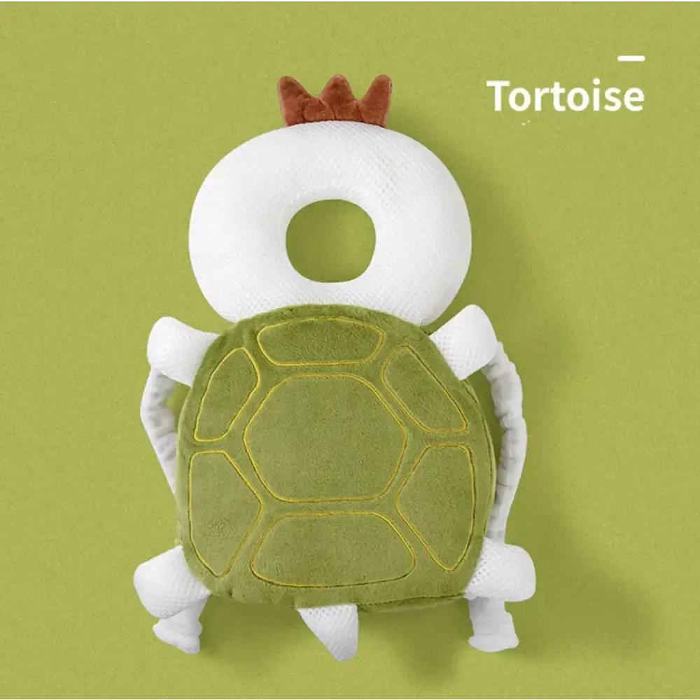 A plush tortoise-shaped baby head support with a white mesh body, green felt shell outlined in yellow stitching, and brown fabric crown.