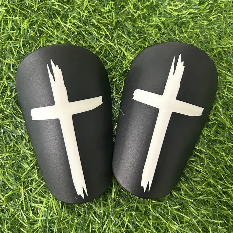 Black soccer shin guards with white cross decals.