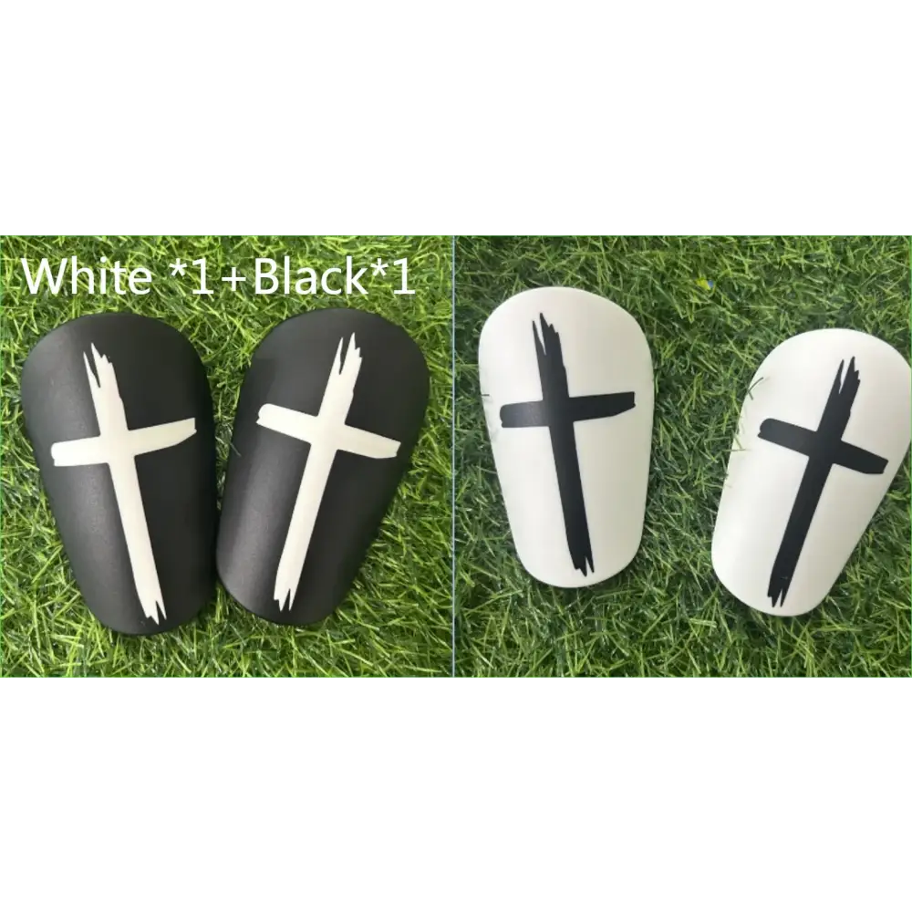 Black and white soccer shin guards with bold cross decals.