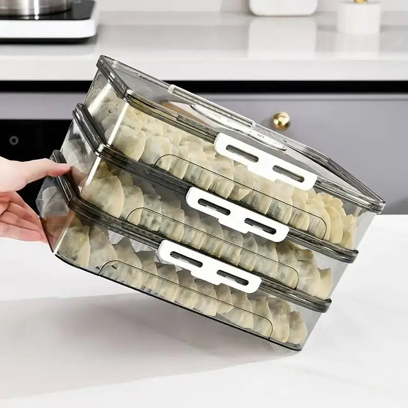 Transparent plastic stackable food storage containers with white latches and black trim, each layer holding neatly arranged dumplings.