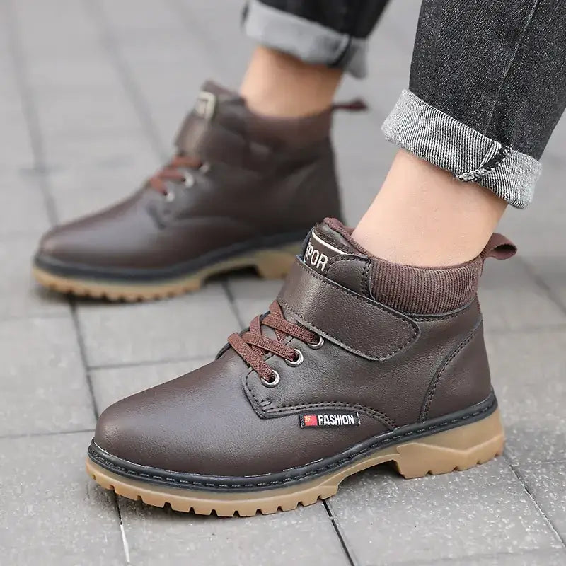 Brown leather ankle boots with matching laces and a tan rubber sole, featuring a velcro strap at the front.