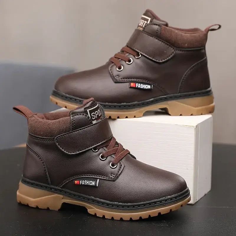 Brown leather ankle boots with a velcro strap, laces, and a tan rubber sole.