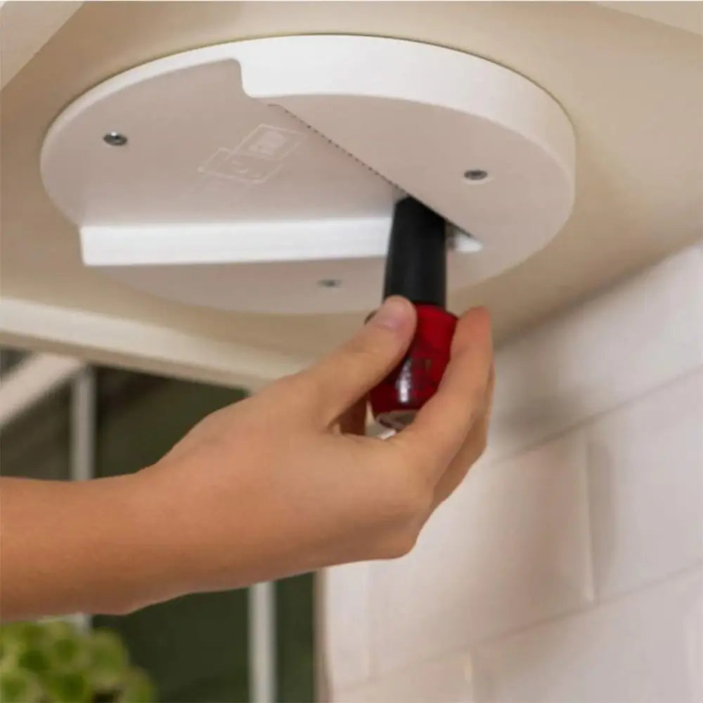 White circular ceiling-mounted nail polish organizer with a slot for storing red bottle of nail polish