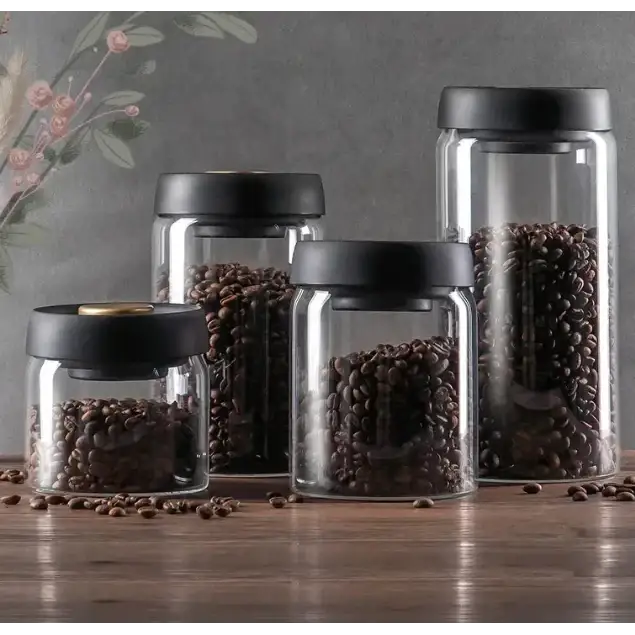 Set of clear glass coffee bean storage jars with black lids, varying in size.