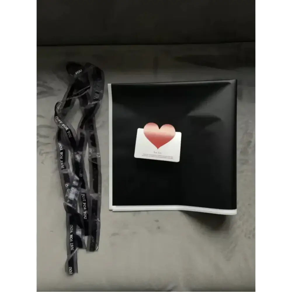 Black gift box with a white card featuring a pink heart sticker on top.