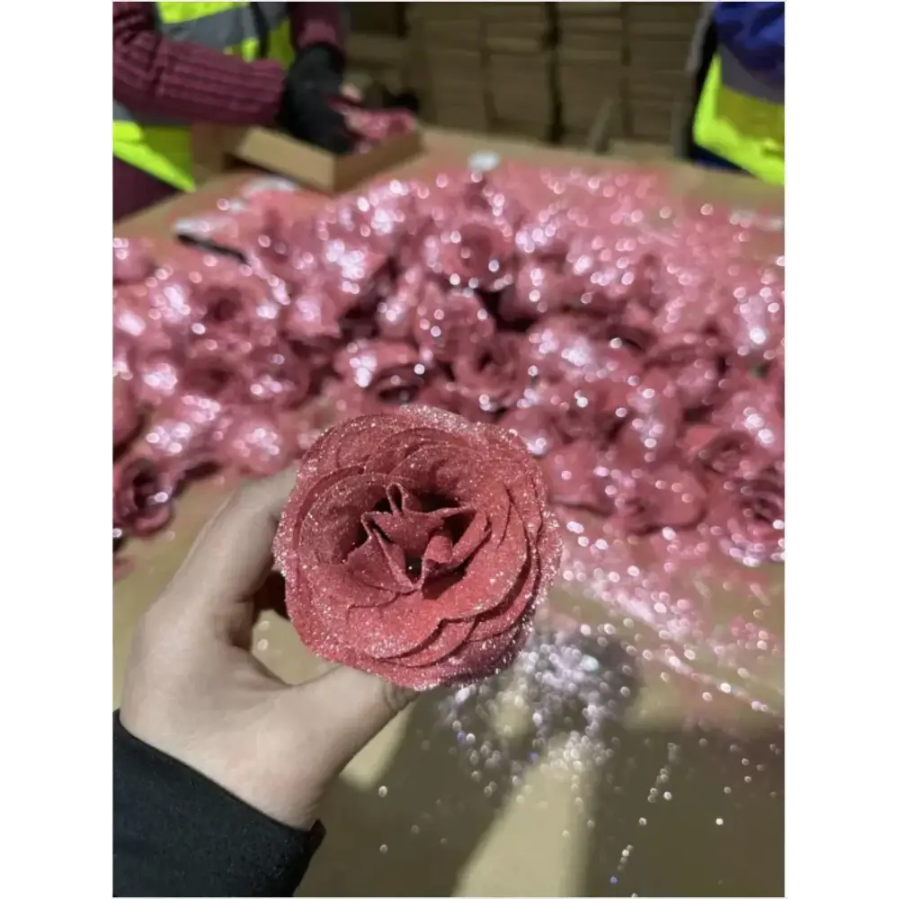 A glittery pink fabric rose with a textured, layered design.