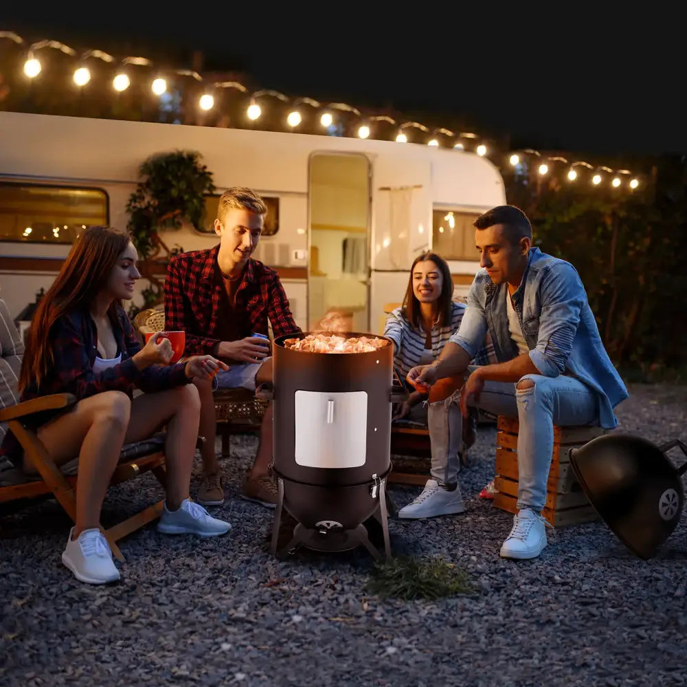Black cylindrical charcoal grill with a white rectangular door and metal legs, featuring a lid resting beside it.