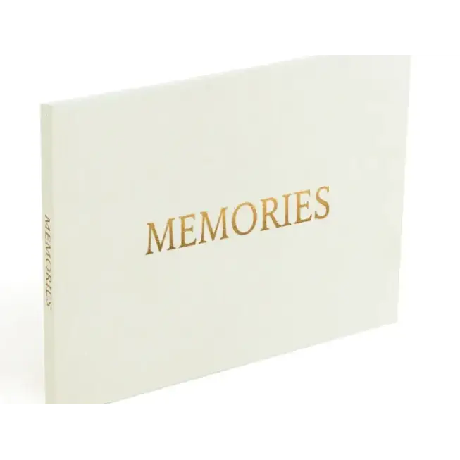 A cream-colored memory book with gold foil lettering that reads ’memories’ on the cover.